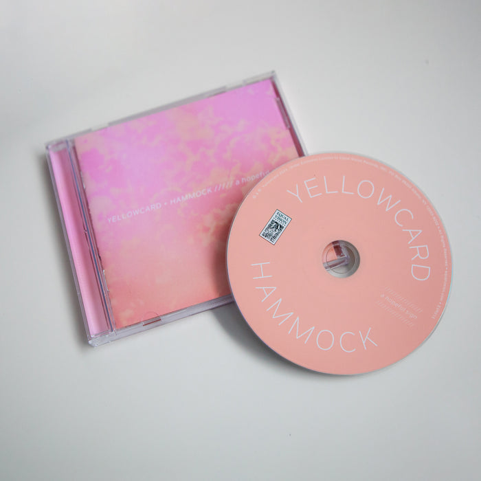A pictue of the CD outside of the case. The CD is a light pink and "YELLOWCARD" HAMMOCK" is printed in white lettering on the top and bottom, respectively.