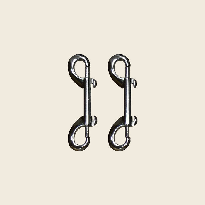 Pair of chrome double-ended snap hooks for Pilates Cadillac and reformer equipment.