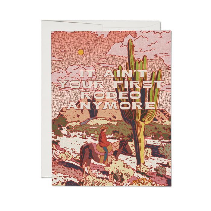 Greeting card with red desert scene and cactus, text: βAinβt it your first rodeo anymore?β