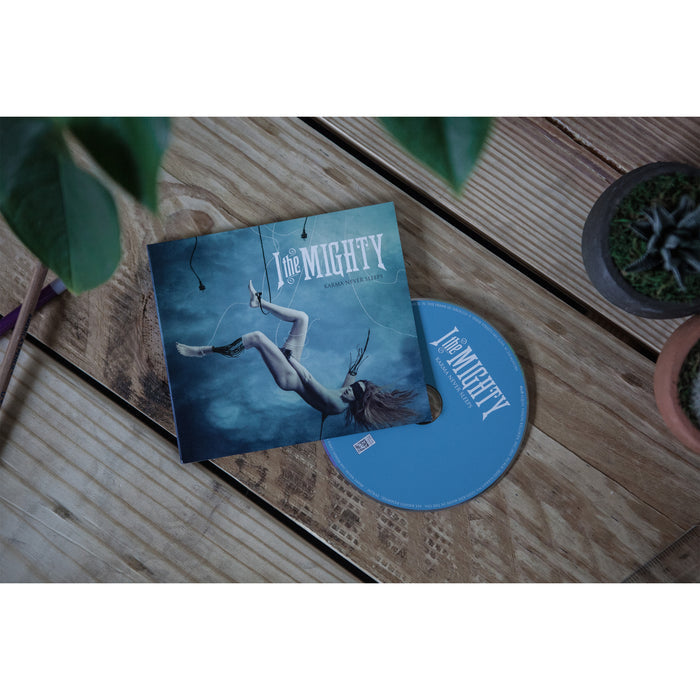 An I The Mighty CD and its case sit on a wooden table near a potted succulent and leafy plant. The EPβs cover shows a person floating underwater, reflecting the ethereal mood of I The Mightyβs music.