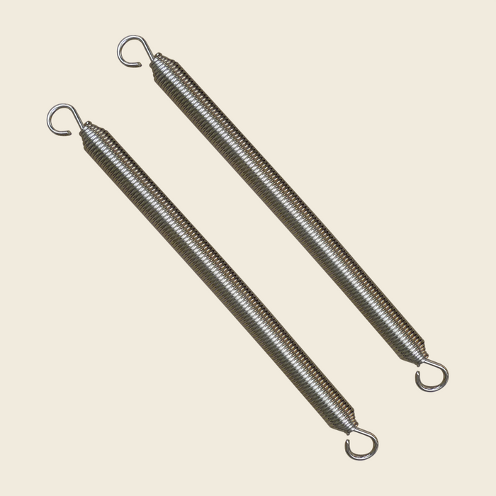 Pair of nickel plated reformer springs with hooked ends on a cream background.