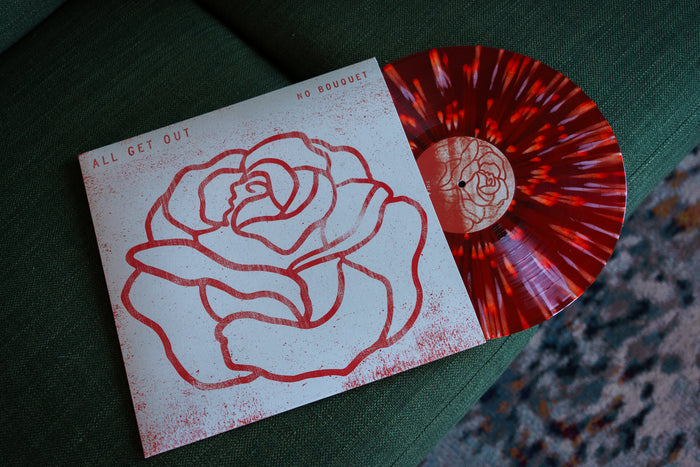 Red vinyl with white and orange splatter peeks out of white jacket with red splatter and a red outline of a rose that takes up the majority of the cover. The words "All get out" are on the left side and "No Bouquet" are on the right side. The vinyl and jacket rests on a green couch.