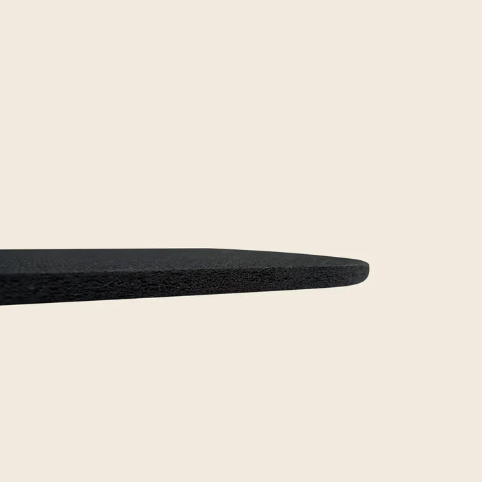 Edge profile of a thin black Pilates rubber pad showing its slim dense thickness.