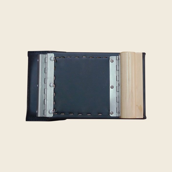 Black leather Pilates reformer head rest with metal hinges and a natural wood block.