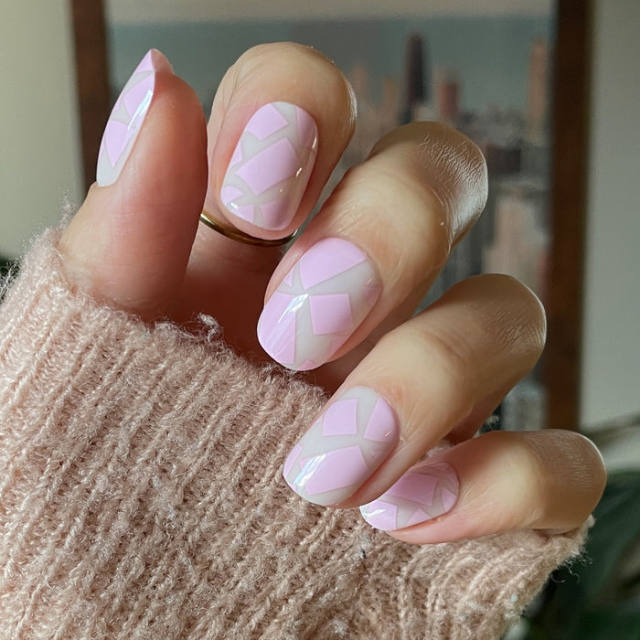 Scattered Squares | Short | Squoval - Tab Press-On light pink press-on nails with geometric square accents on hand in soft knit sleeve