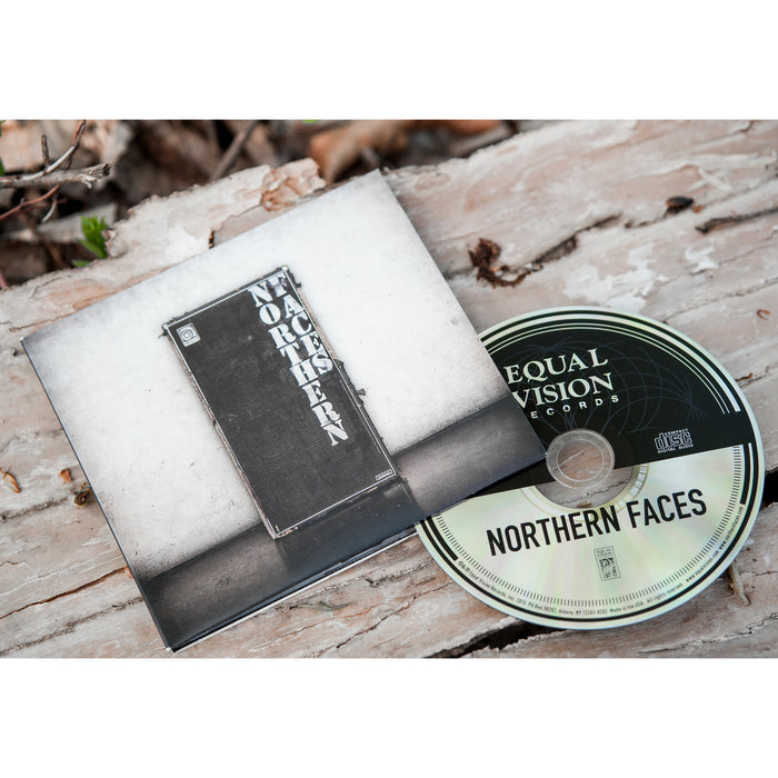 A Northern Faces self-titled CD and its album cover are placed on a weathered wood surface. The album cover shows a black speaker cabinet with the brand name, Northern Faces, printed vertically.