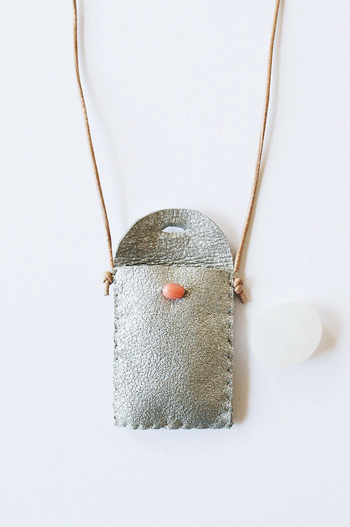 Textured silver-toned amulet pouch necklace with red bead front and cord ties