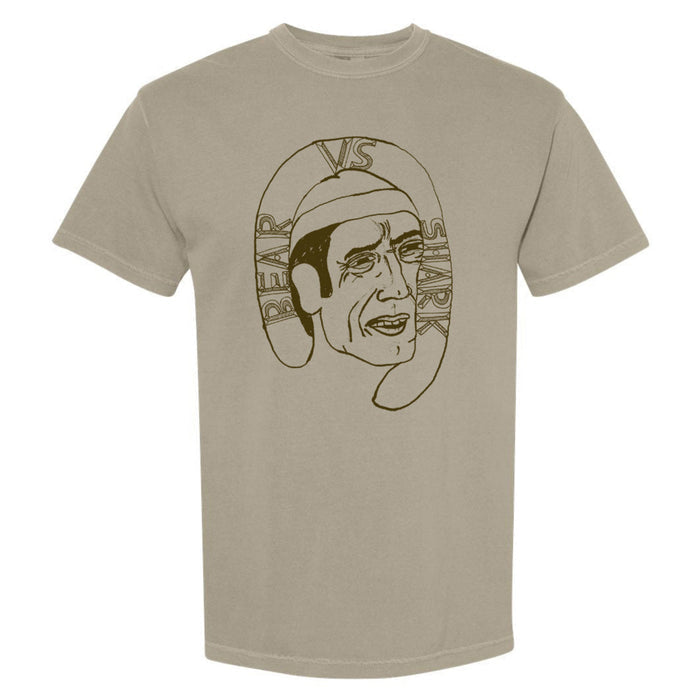 A sandy colored shirt has a sketch of an older man with the words "bear vs shark" wrapped around the top of his head.