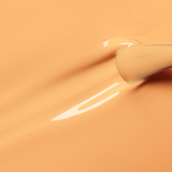 A close-up of a Manucurist Abricot nail polish brush applying glossy apricot orange gel polish in smooth strokes on a matching background.