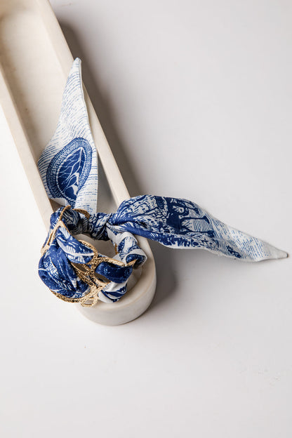 White ceramic with a blue and white patterned cloth tied around it on a light gray background