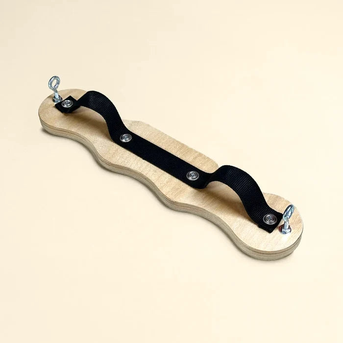Pilates foot corrector with wavy-edge wooden board, black canvas strap, and metal eye bolt hardware for arch and ankle strengthening.
