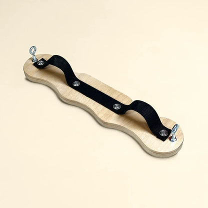Pilates foot corrector with wavy-edge wooden board, black canvas strap, and metal eye bolt hardware for arch and ankle strengthening.