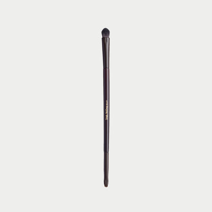 A single makeup brush with a dark brown handle and black bristles, featuring gold text that reads 'The Makeup Club' on a light gray background.