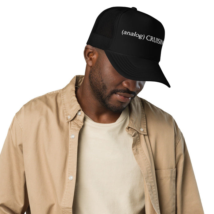 Male model wearing black (analog) CRUISING foam trucker hat with white embroidery, right front view, Adam's Nest Provincetown