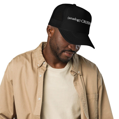 Male model wearing black (analog) CRUISING foam trucker hat with white embroidery, right front view, Adam's Nest Provincetown
