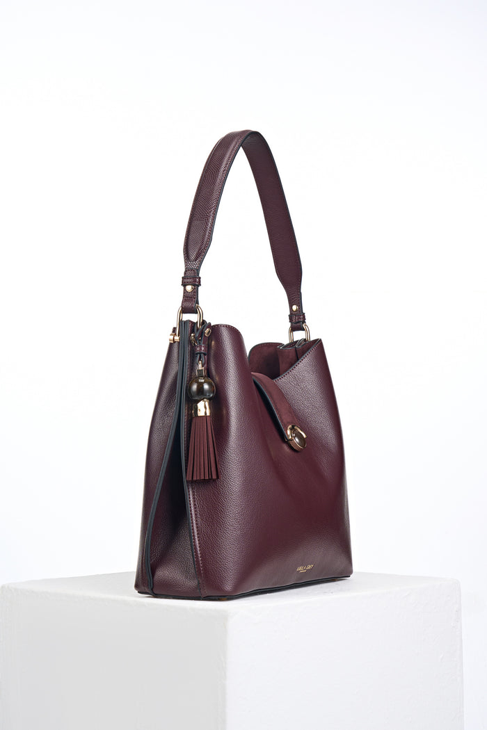 Side view of the Andrea Black Cherry faux leather Hobo shoulder bag showing the Thames Tassel Charm attached to the shoulder strap