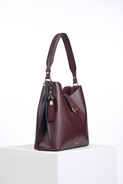 Side view of the Andrea Black Cherry faux leather Hobo shoulder bag showing the Thames Tassel Charm attached to the shoulder strap