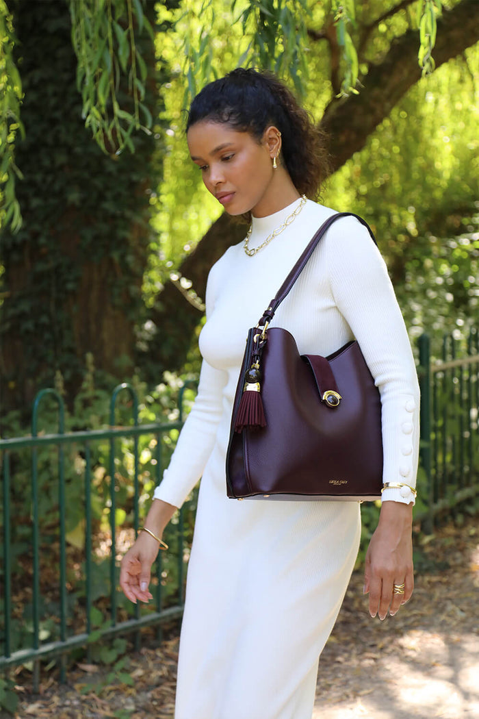 Female model wearing Andrea Black Cherry faux leather Hobo shoulder bag over one shoulder while walking