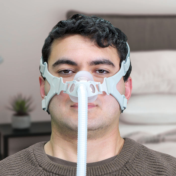 Man wearing a CPAP mask with a blurred indoor background