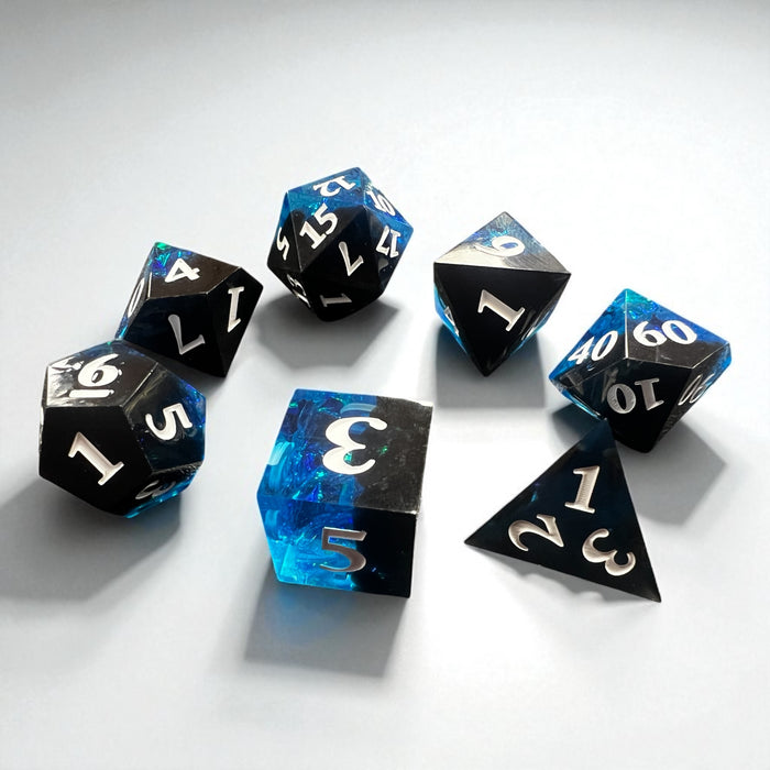 7-piece Black and Blue Prismatic RPG Dice Set with swirling resin and glitter, ideal for cosmic and dark fantasy campaigns.