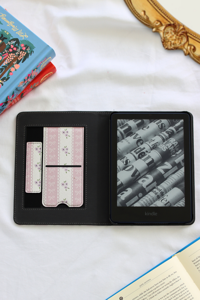 Kindle device in a case on a white surface with books in the background