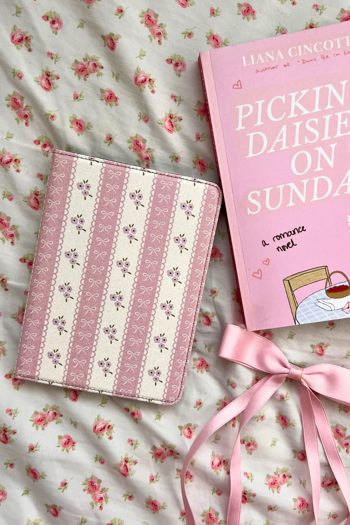 Pink kindle and book on a floral fabric background