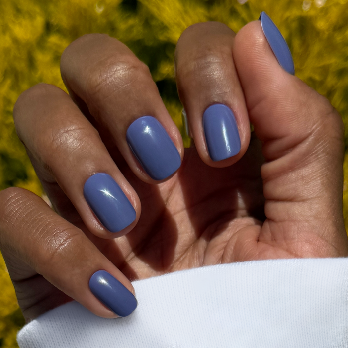 Hand with Bootcut | Short | Squoval - Tab Press-On nails in smooth denim blue shade against blurred yellow background