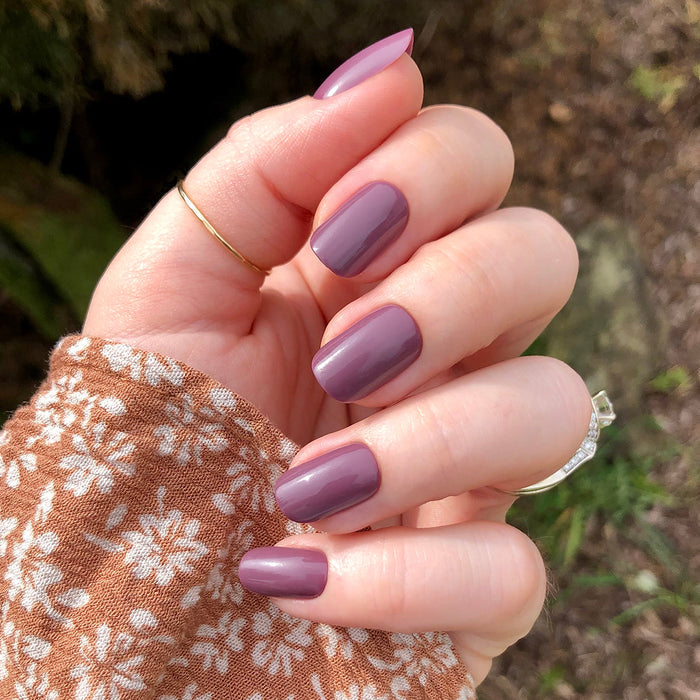 Cardigan | Short | Squoval - Tab Press-On nails in true mauve shade with glossy finish on hand outdoors in floral brown sleeve