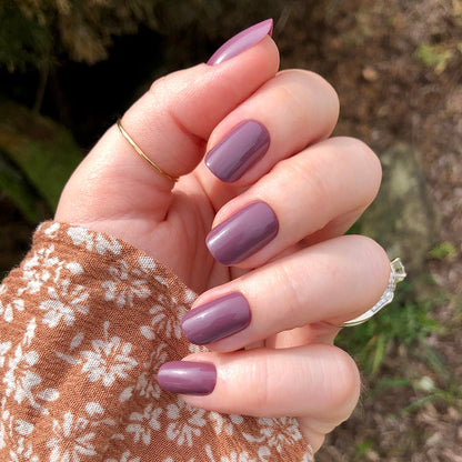 Cardigan | Short | Squoval - Tab Press-On nails in true mauve shade with glossy finish on hand outdoors in floral brown sleeve