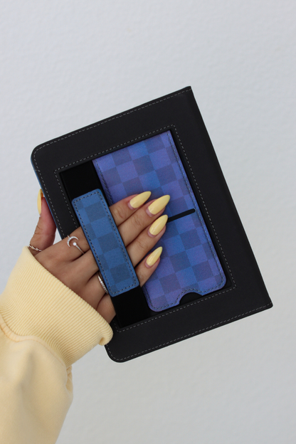Hand holding a black leather-bound book with a blue checkered interior on a light gray background