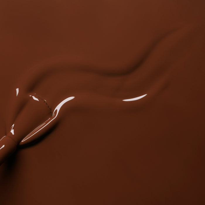 Close-up of smooth, melted chocolate with a glossy, swirling pattern—reminiscent of Manucurist's Chestnut gel polish.