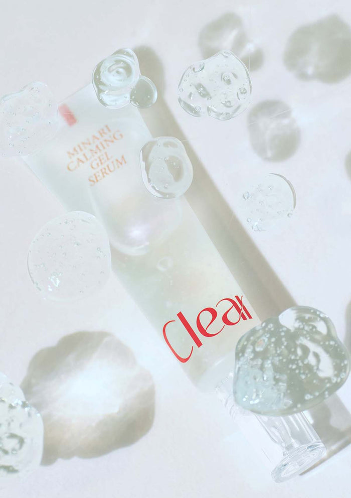 Skincare serum bottle with droplets on a light background