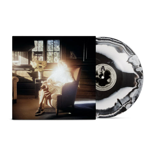 A Black with White marbled vinyl from Common Sage is partially pulled out of its sleeve, which shows a glowing, backlit figure in an armchair by a window in a sunlit rustic room. Ships via USPS Priority Mail.
