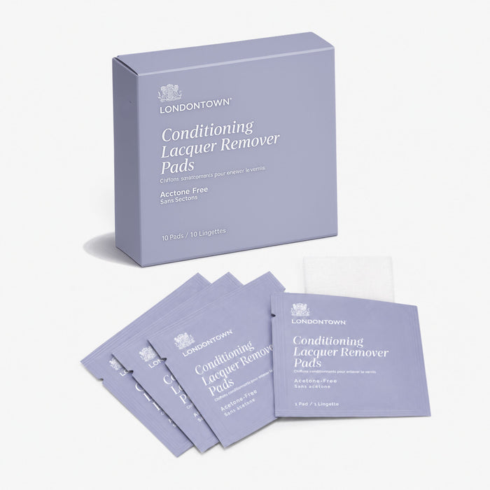 A box labeled “LONDONTOWN Conditioning Lacquer Remover Pads” is shown with individual purple packets and one unfolded pad displayed in front, offering a convenient on-the-go solution for effortless nail polish removal.