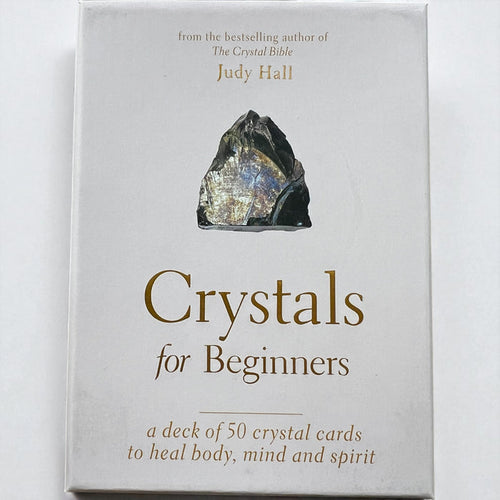 Card deck packaging titled 'Crystals for Beginners' by Judy Hall on a white background, Raven's Cauldron, 6 N Sandusky St, Delaware, OH 43015