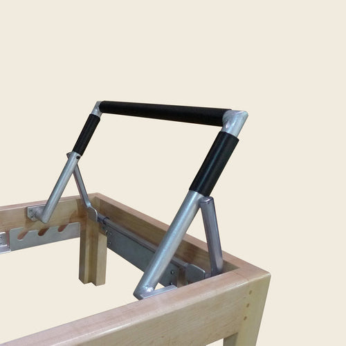 Black direct contact foot bar cover fitted on a wooden Pilates Reformer's aluminum bar.