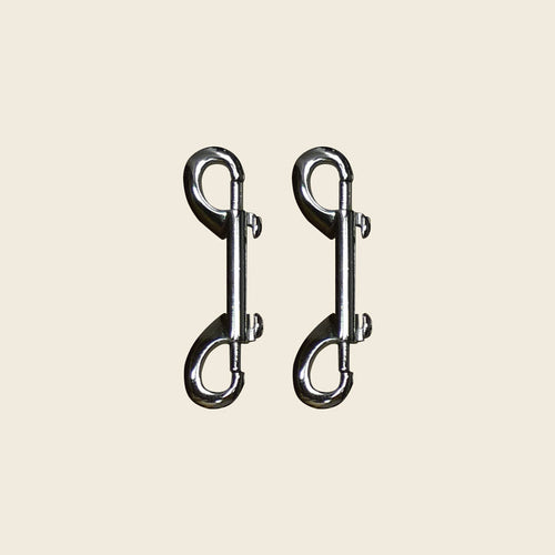 Pair of chrome double-ended snap hooks for Pilates Cadillac and reformer equipment.