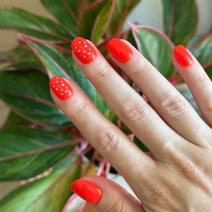Festive Stars | Extra Short | Round - Tab Press-On nails in bright cherry red with tiny white star accents on natural hand