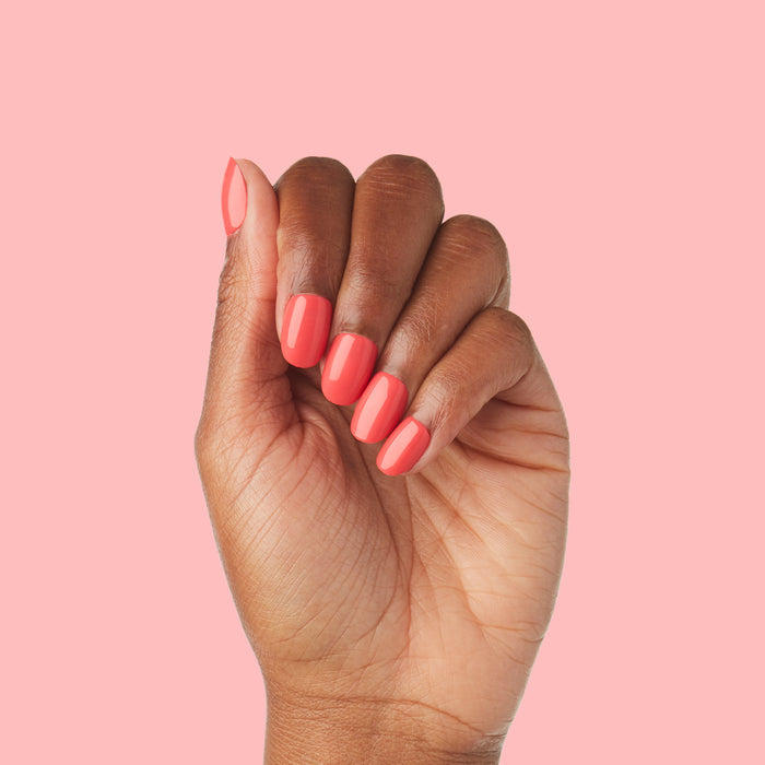 Hand with Field Day | Round | Extra Short press-on nails in juicy watermelon red glossy finish on natural skin tone against pink background