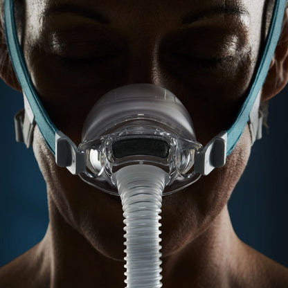 Close-up of a person wearing a CPAP mask against a dark background