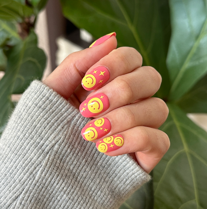Happy All Over | Short | Round - Tab Press-On nails with pink base and yellow smiley face and star motifs for a playful mani look