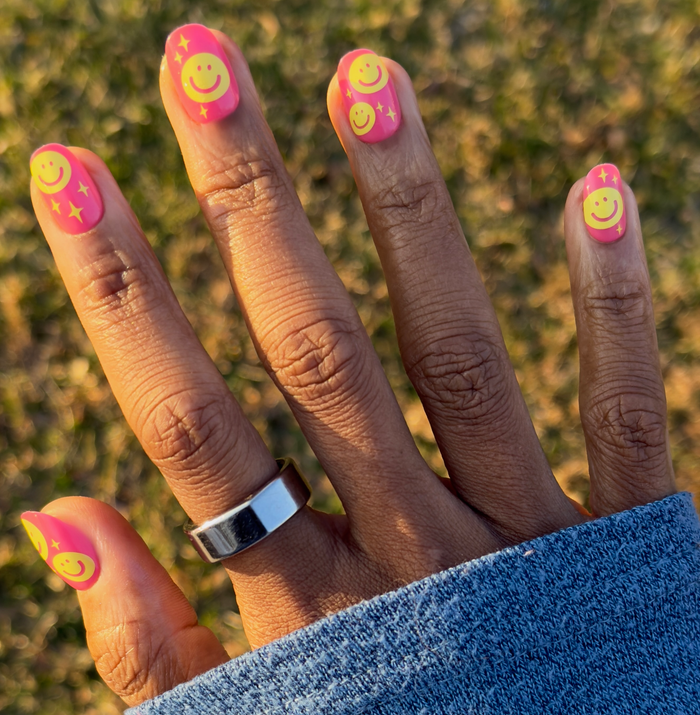 Happy All Over | Short | Round - Tab Press-On nails with pink base and yellow smiley face and star details for a bright mani look