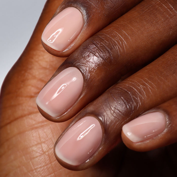 A close-up of a hand with neatly manicured nails featuring LONDONTOWN High Gloss Top Coat, showcasing a light pink polish and radiant glass-like shine.