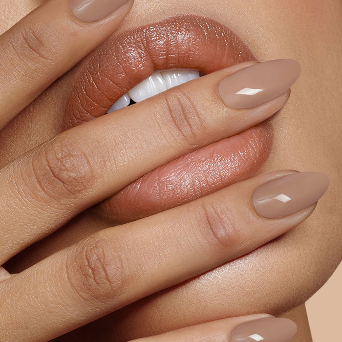 Close-up of lips and fingers with a nude manicure, featuring a subtle glass shine created by LONDONTOWN's High Gloss Top Coat.