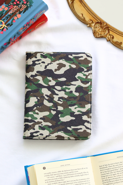 Camouflage-patterned kindle on a white surface with books in the background