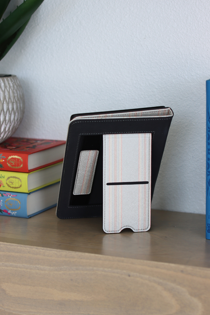Kindle case on a wooden surface with books in the background
