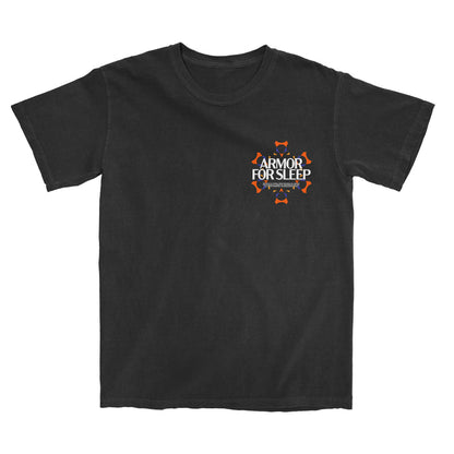 A black Comfort Colors t-shirt by Armor For Sleep with an orange and white design on the left chest, surrounded by small orange shield icons.