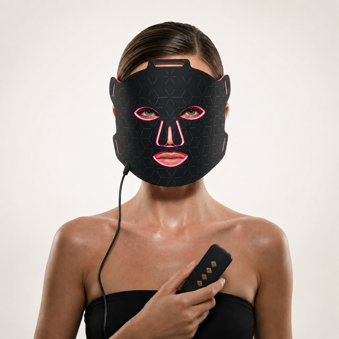 Woman wearing Luminmax LED red light therapy face mask and holding controller