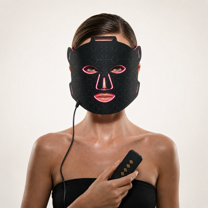 Woman wearing Luminmax LED red light therapy face mask and holding controller