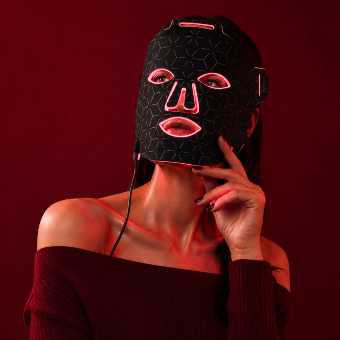 Luminmax LED red light therapy mask glowing in use against a red background for professional at-home skincare